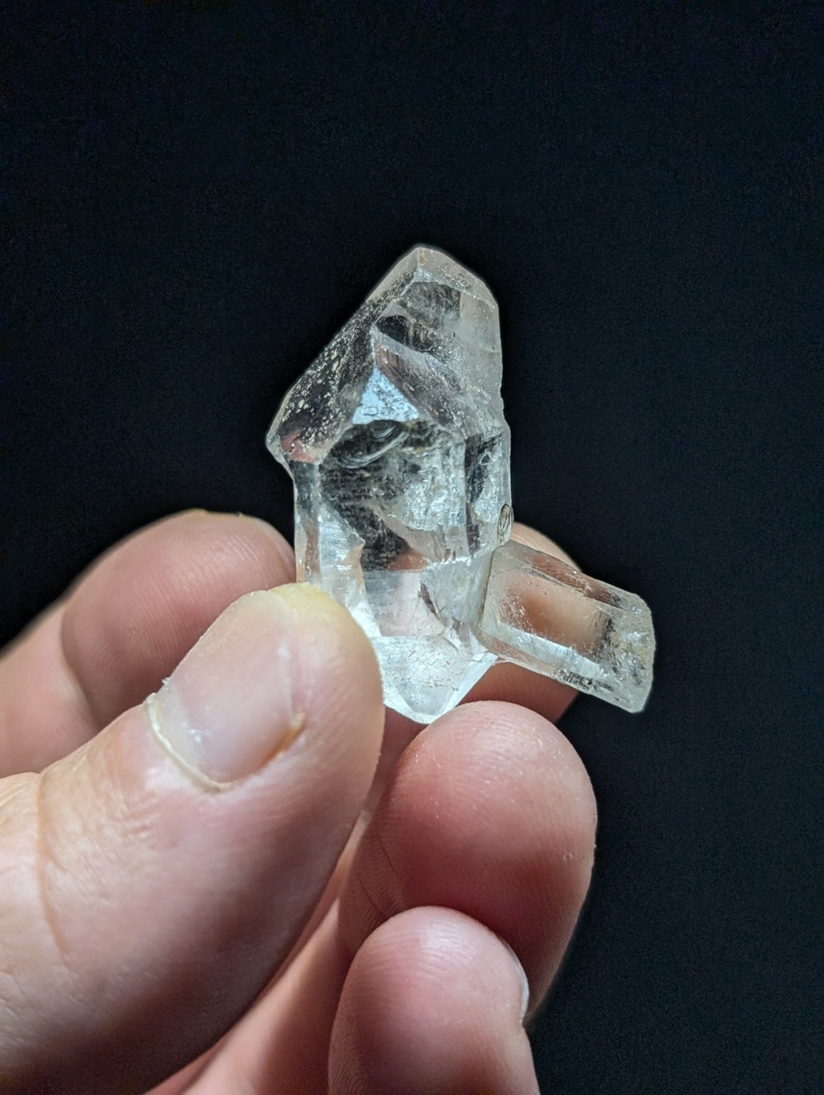 A clear, faceted quartz crystal with a natural, jagged growth pattern and two distinct prismatic points.