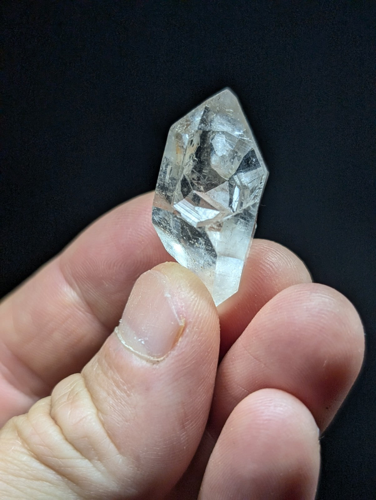 A clear, faceted quartz crystal with a pointed tip and natural internal inclusions.
