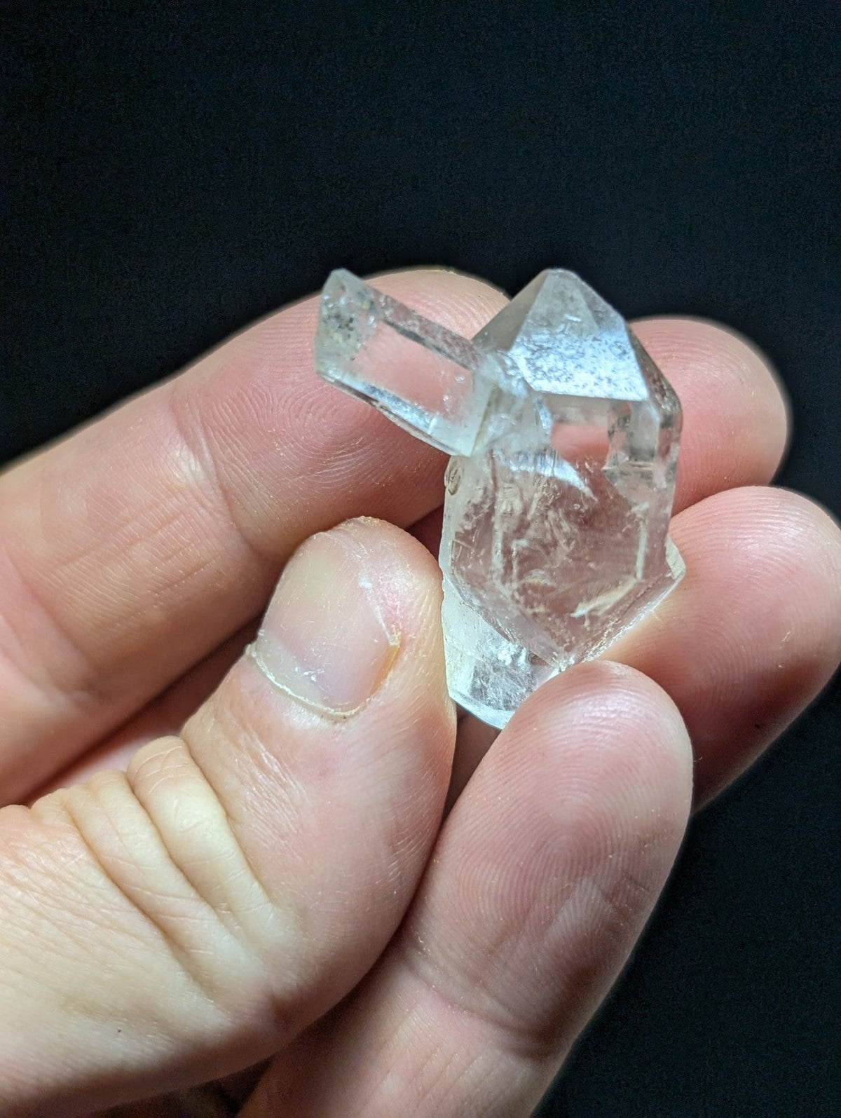 A clear, faceted quartz crystal with a pointed top and natural inclusions.