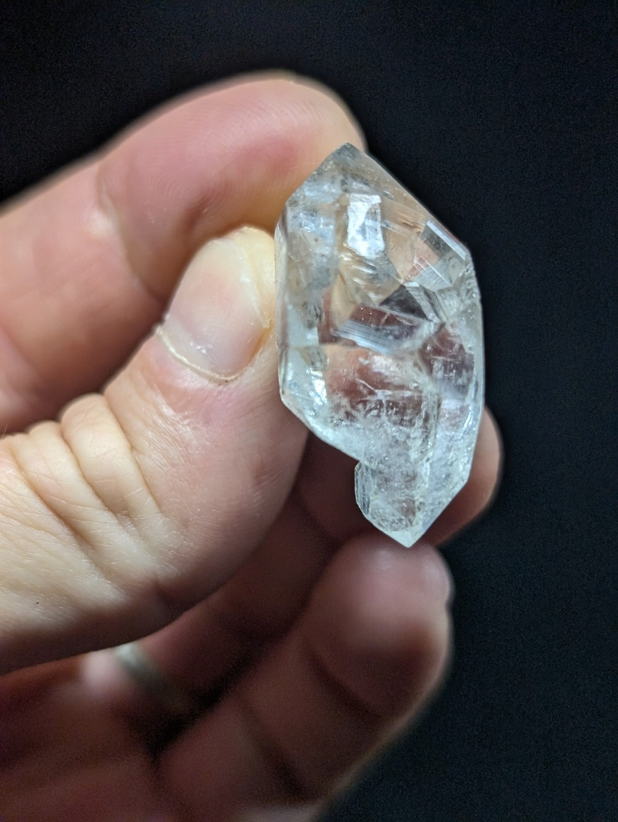 A clear, faceted quartz crystal held in a hand.