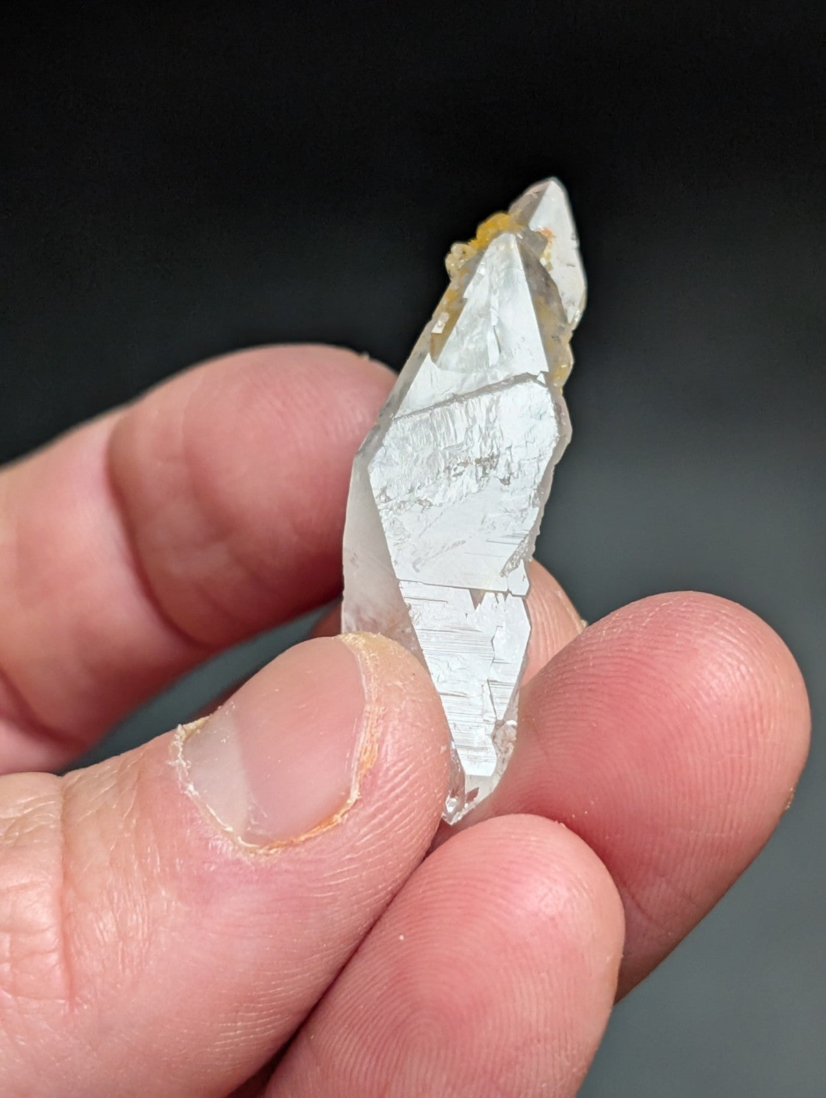 A translucent, clear quartz crystal with a pointed tip and visible internal striations.
