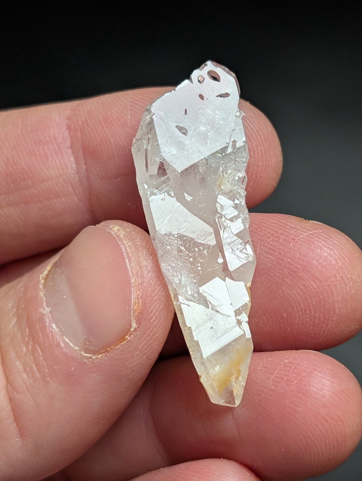 A translucent, clear quartz crystal with a pointed tip and natural facets.