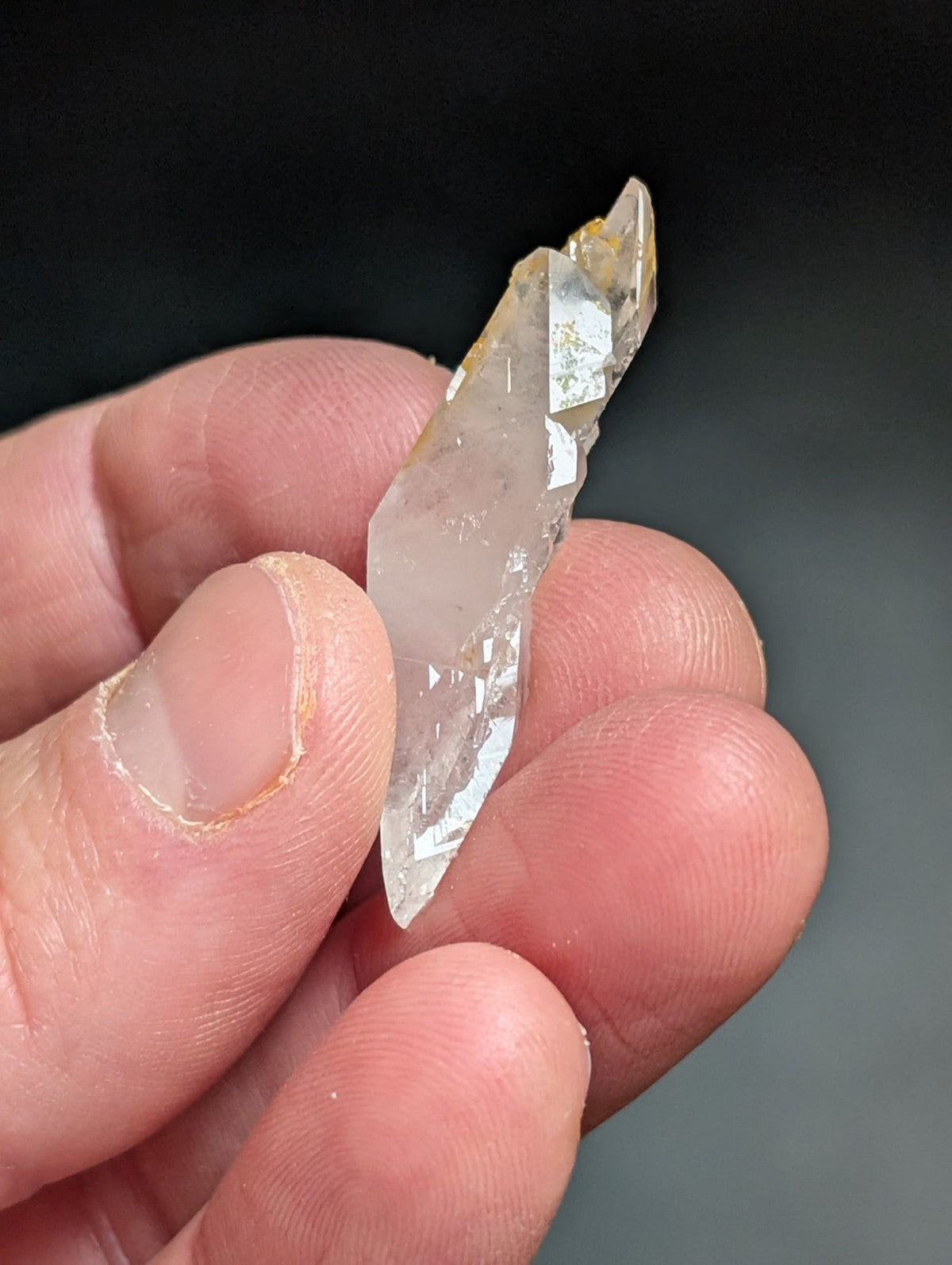 A translucent, clear quartz crystal with a pointed tip and subtle golden inclusions.