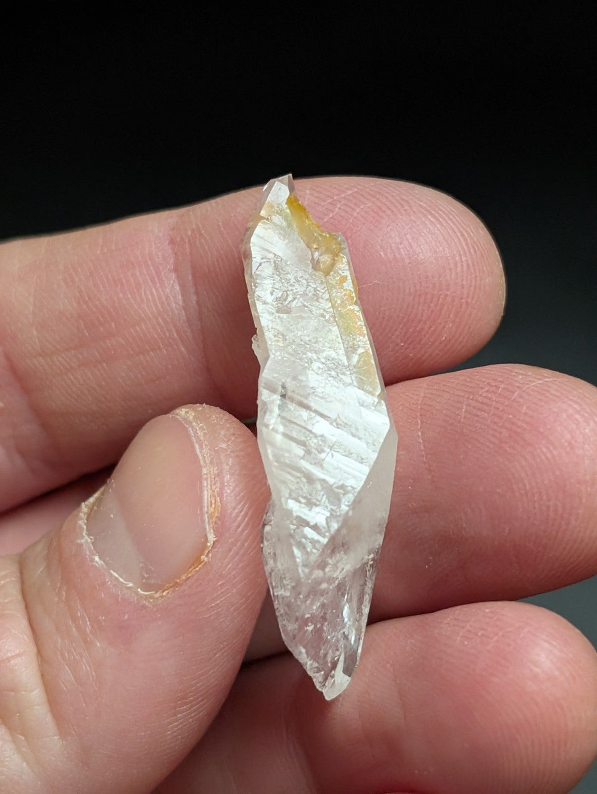 A translucent, clear quartz crystal with a pointed tip and visible internal striations.