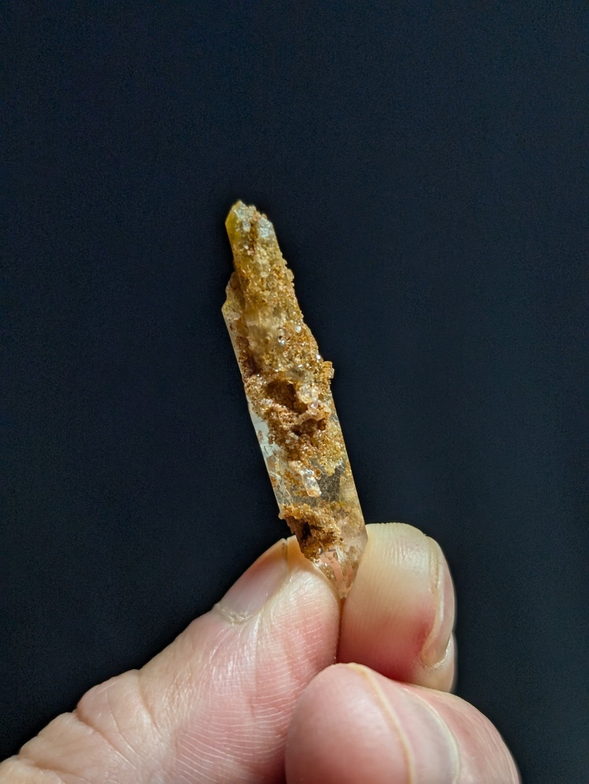 A translucent, amber-hued crystal with a rough, earthy surface and pointed tip.