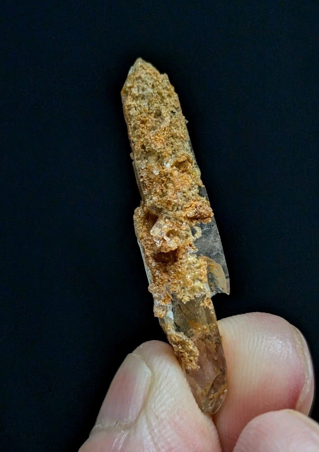 A translucent, amber-hued quartz crystal with a rough, earthy coating and visible internal crystalline structure.