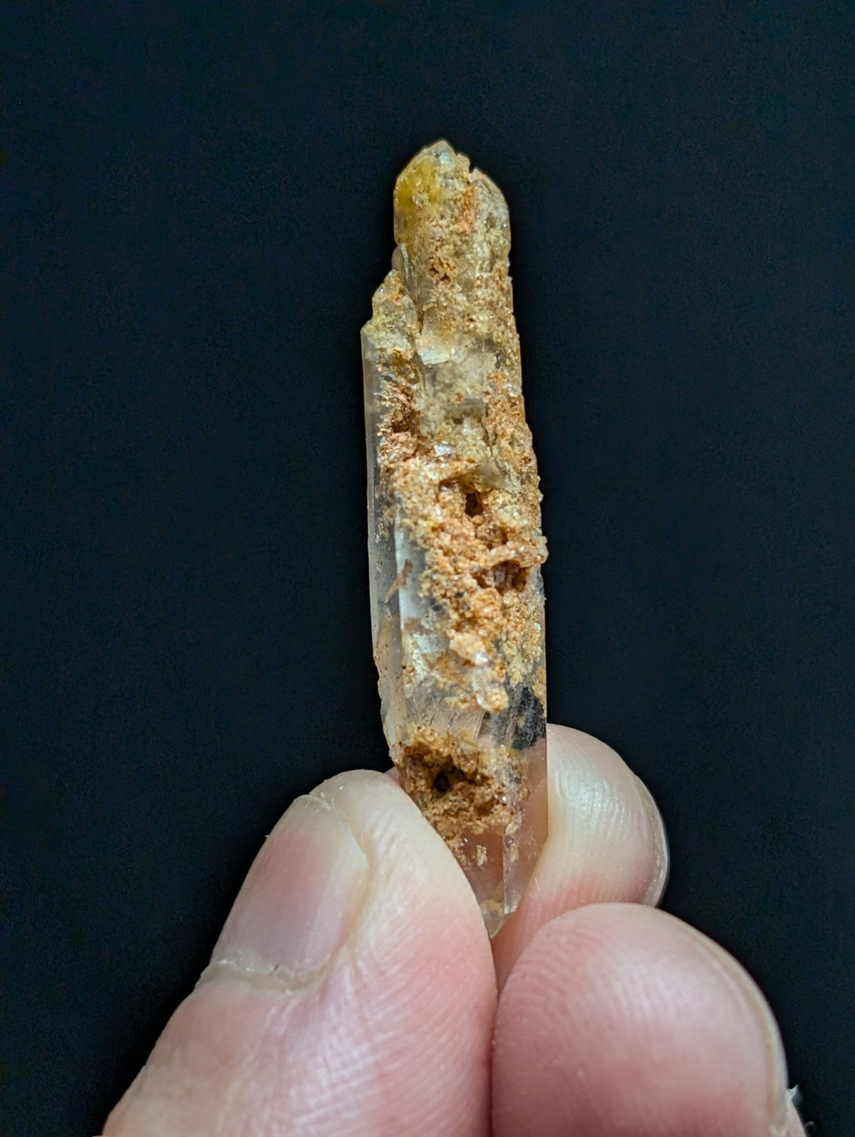 A translucent yellowish quartz crystal with a rough, earthy coating and natural imperfections.