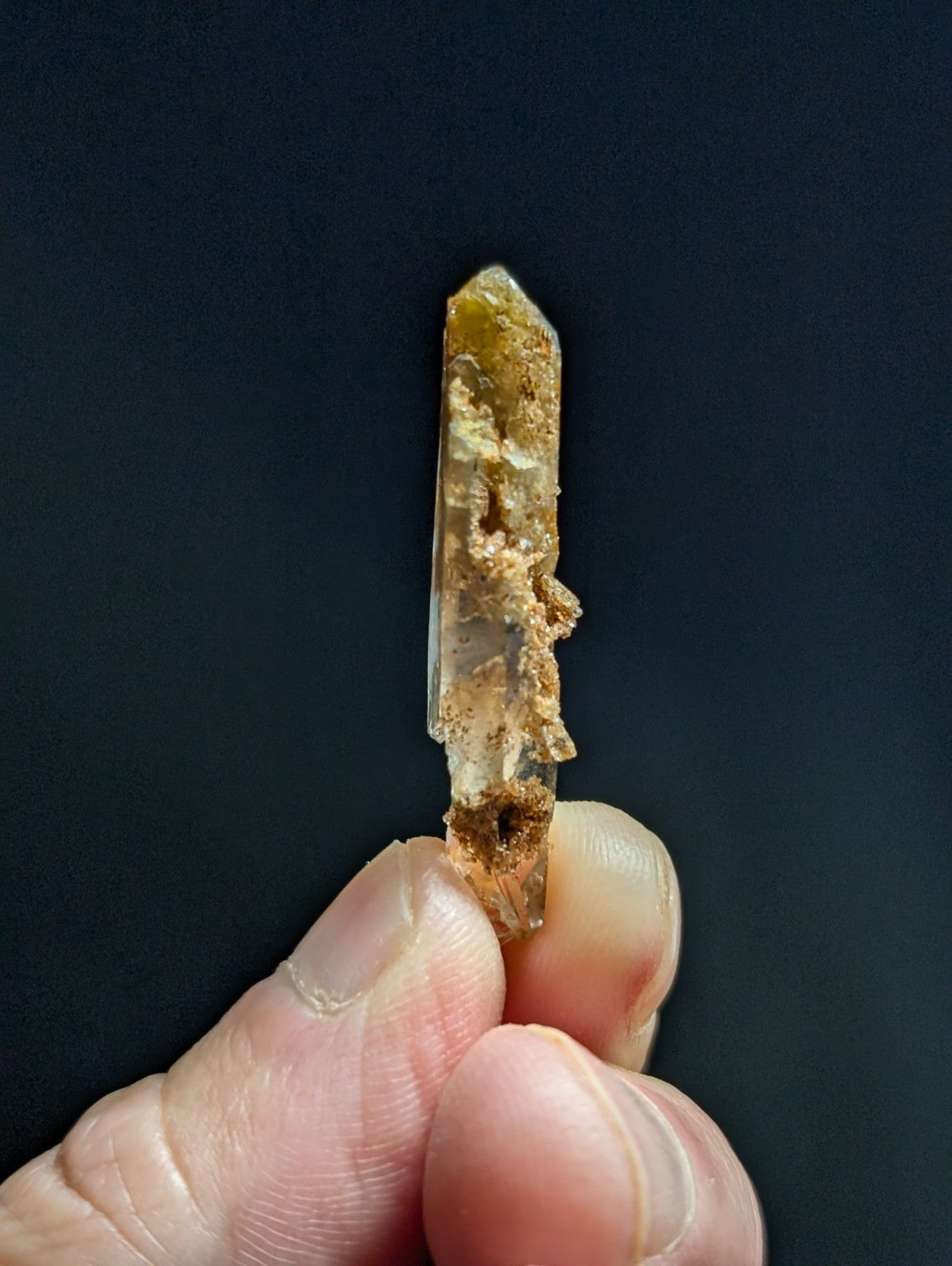 A translucent, amber-tinted quartz crystal with a rough, earthy base and pointed tip.