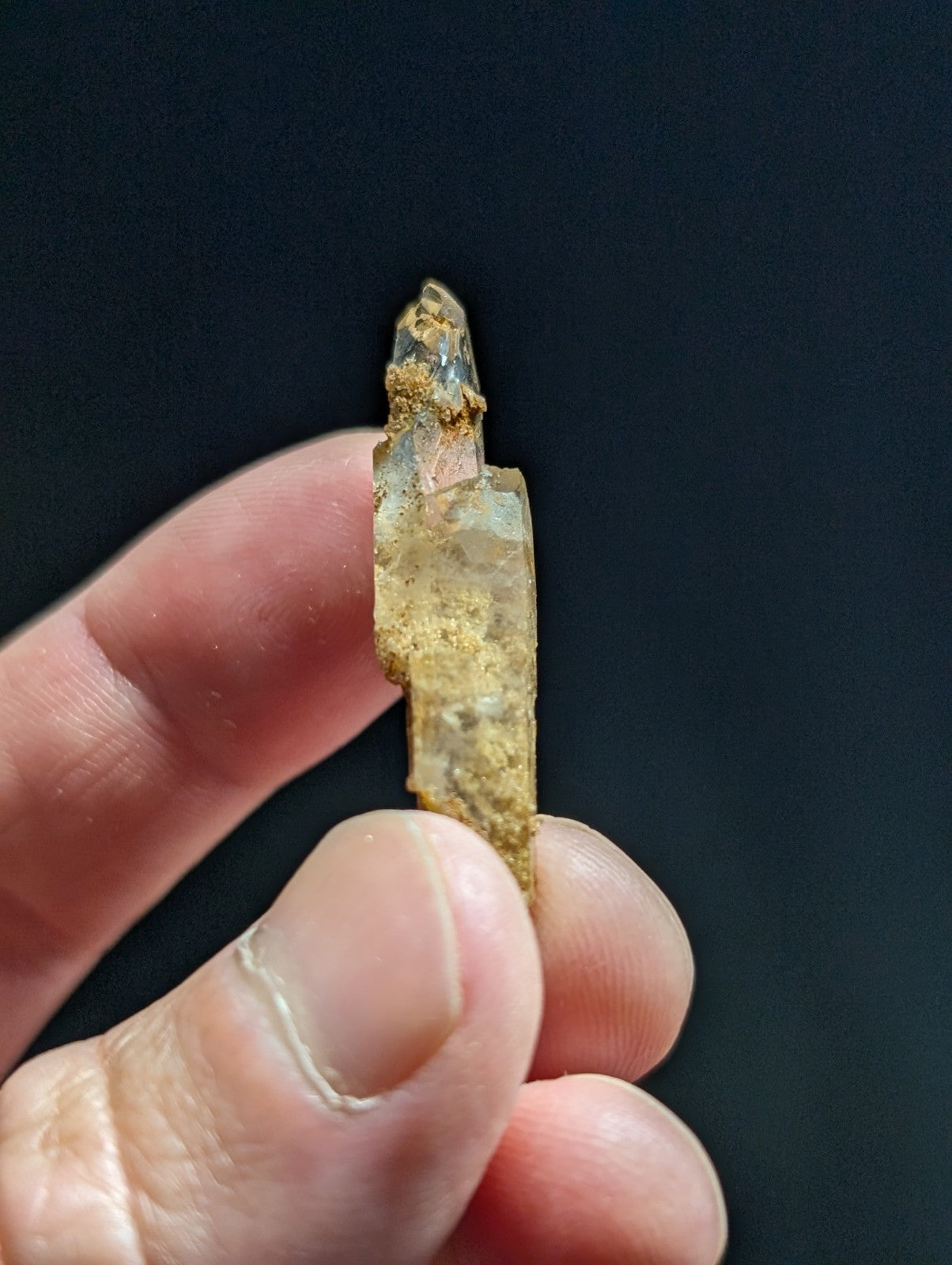 A translucent, amber-hued crystal with a rough, earthy surface and pointed tip.