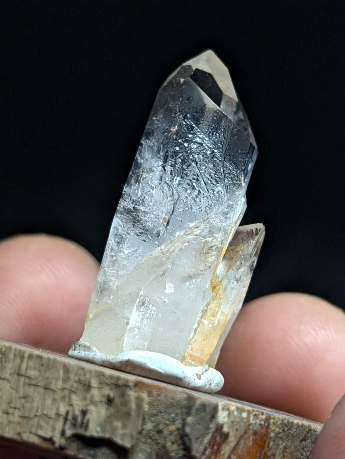 A clear, translucent quartz crystal with a pointed tip and visible internal inclusions.