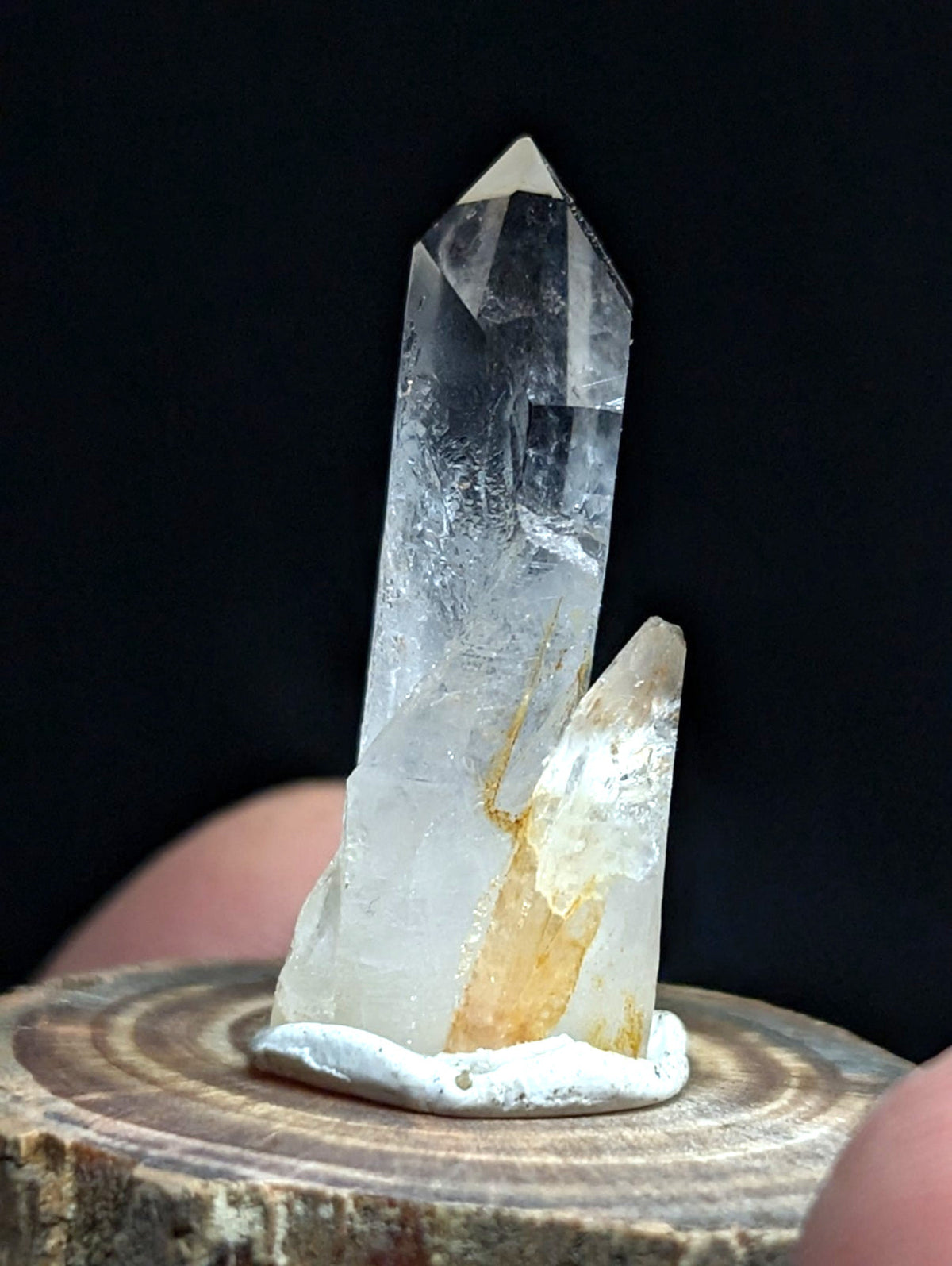 A clear quartz crystal cluster with a tall, pointed main spike and smaller adjacent spikes, featuring subtle golden inclusions along its base.