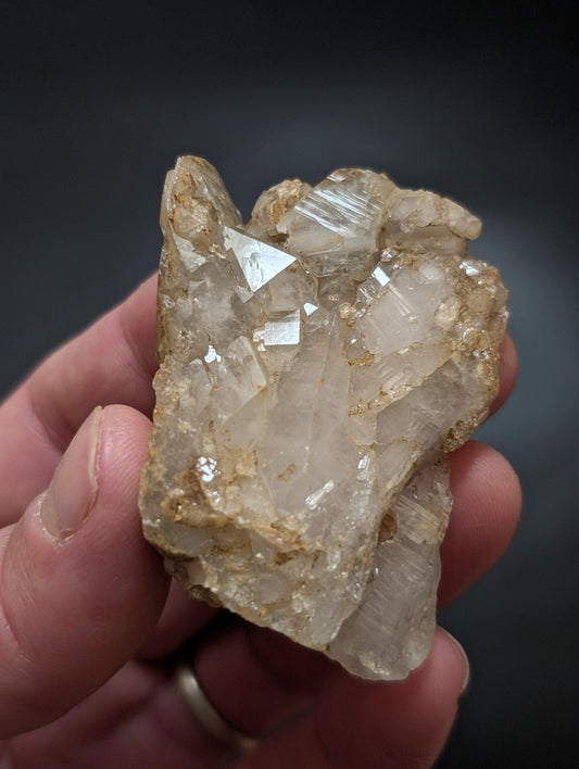 A translucent, crystalline quartz cluster with clear facets and golden-brown matrix.