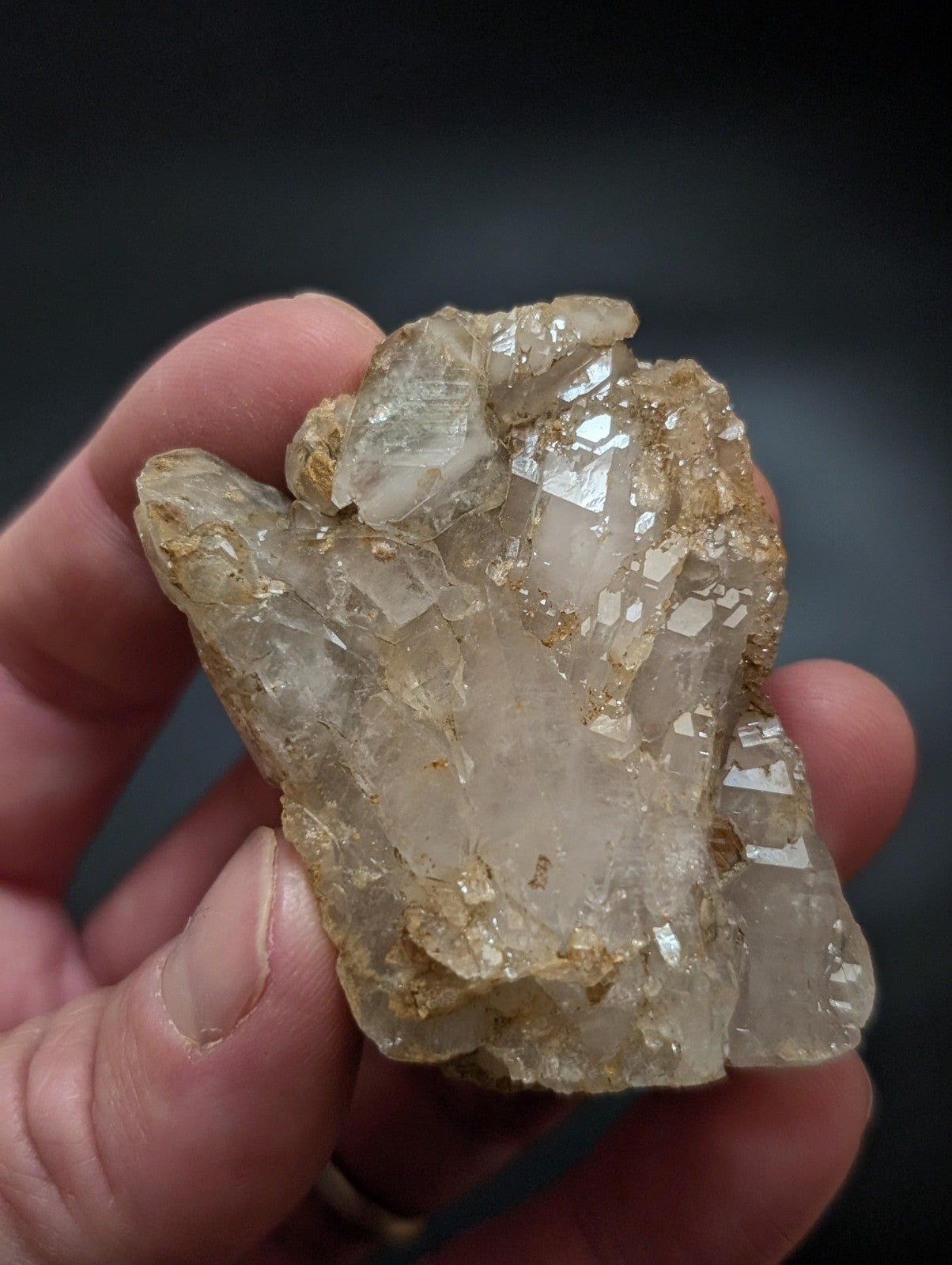 A translucent, pale quartz crystal cluster with golden-brown mineral inclusions and sharp geometric facets.