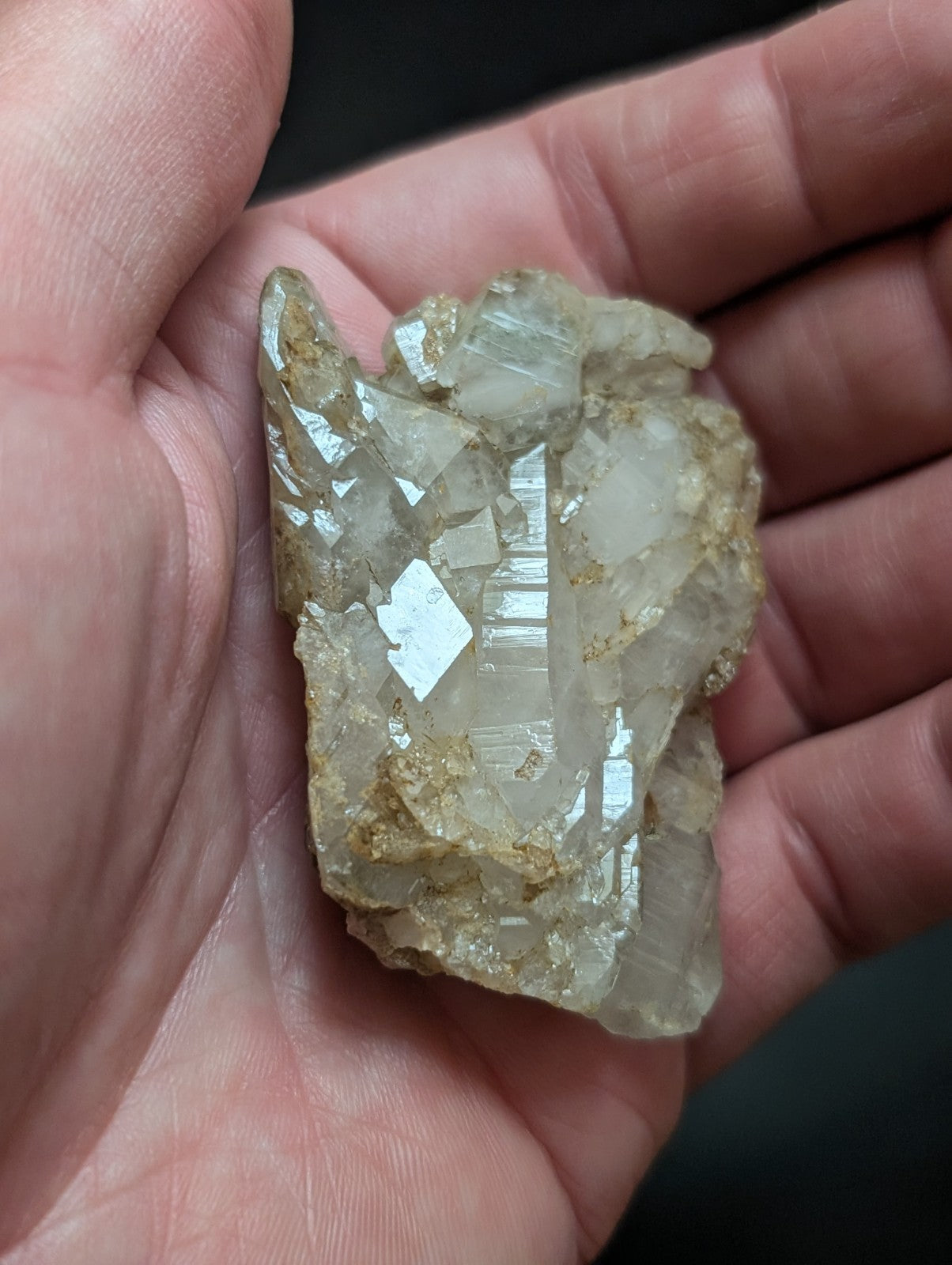A translucent, pale quartz crystal cluster with golden mineral inclusions and sharp, faceted edges.
