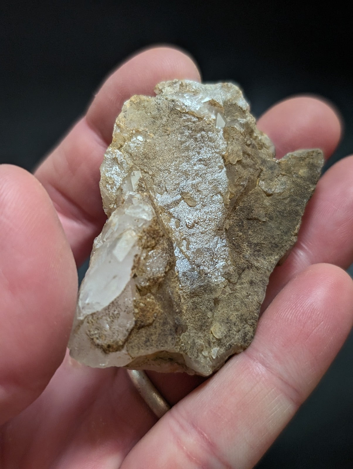 A rough, earthy-toned quartz crystal cluster with translucent white and grayish facets nestled in a rocky matrix.