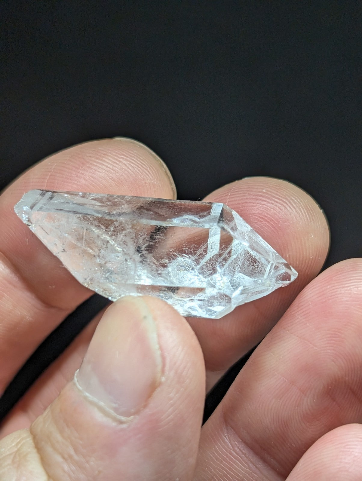 A clear, faceted quartz crystal with natural inclusions and a pointed tip.