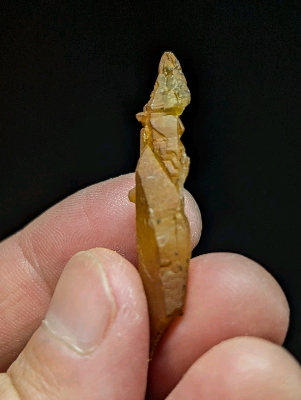 A translucent amber-colored, intricately carved stone pendant with a pointed top and layered design.