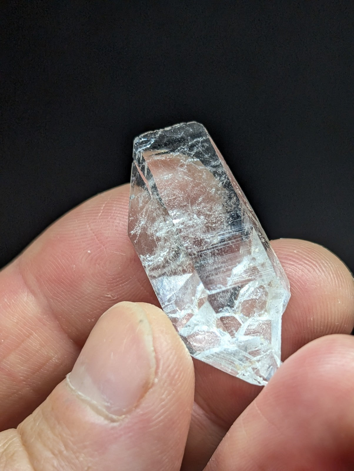 A clear, faceted quartz crystal with natural internal inclusions and a pointed tip.