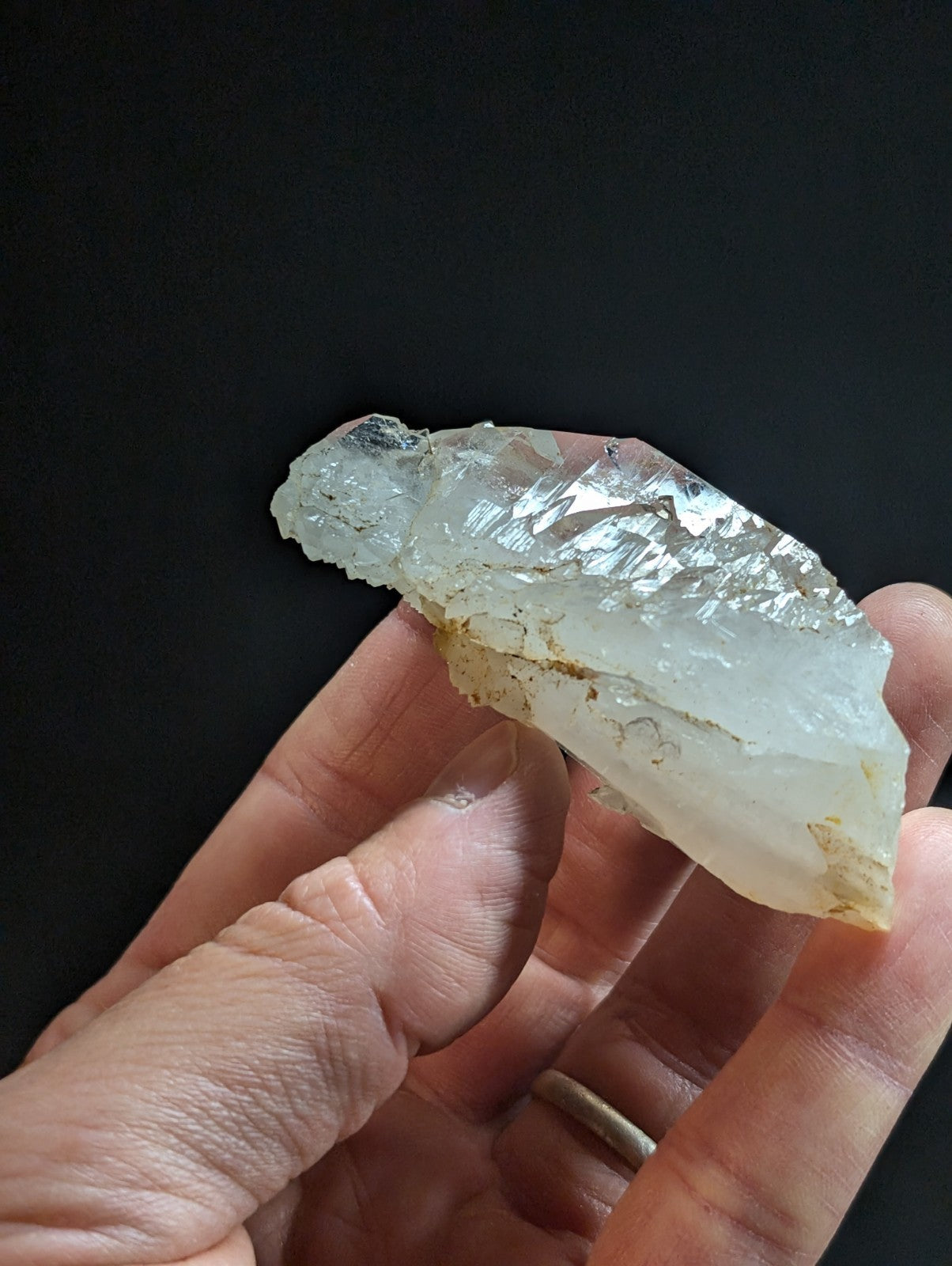 A translucent, pale quartz crystal with a rough, jagged surface and subtle golden inclusions.