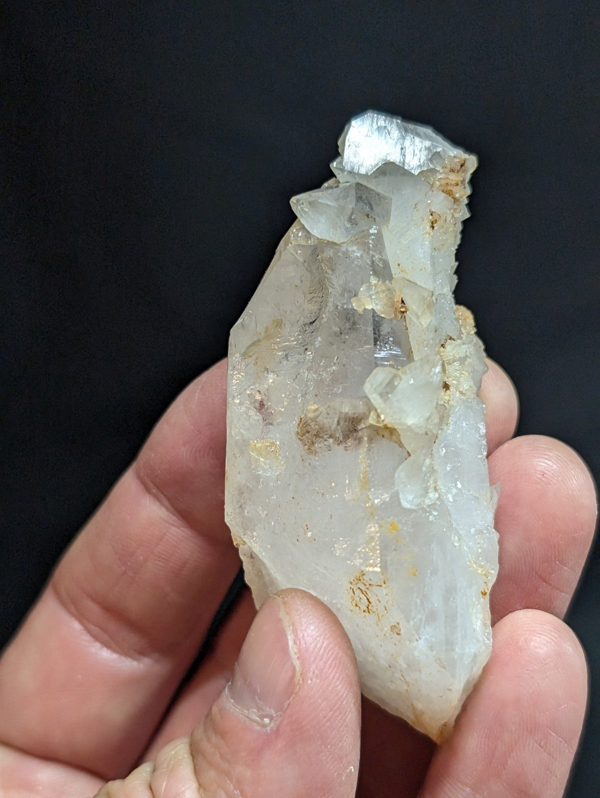 A translucent, pale quartz crystal cluster with golden mineral inclusions and a rough, jagged surface.