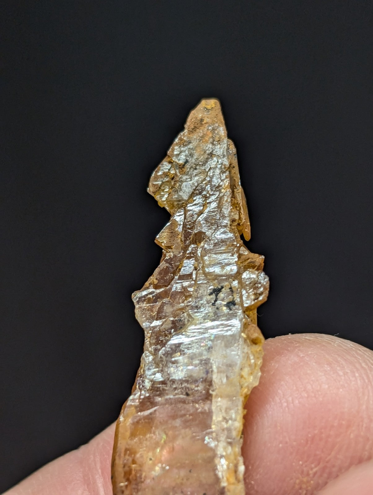 A translucent amber-colored crystal with a rough, jagged surface and visible internal striations.
