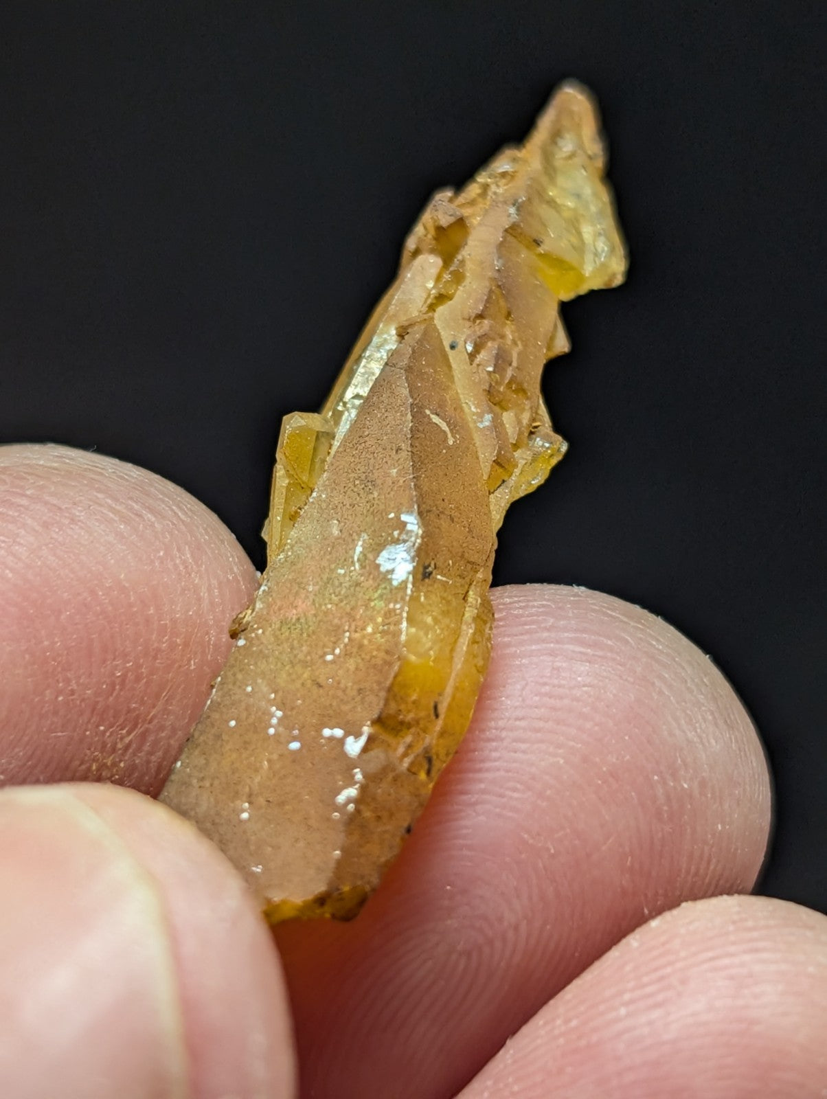 A translucent amber-colored crystal with a jagged, natural edge and subtle internal inclusions.