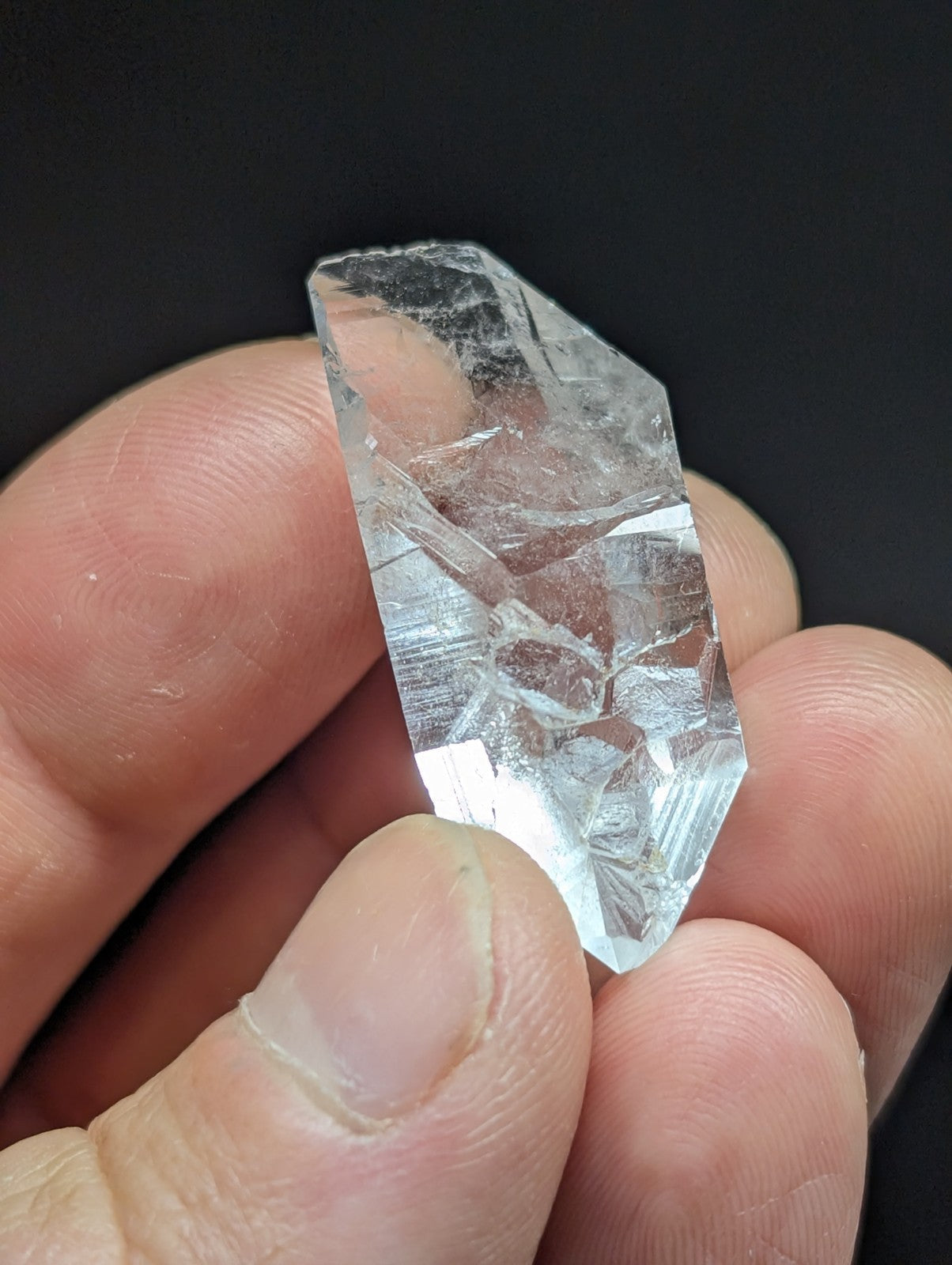 A clear, faceted quartz crystal with natural internal inclusions and a pointed tip.