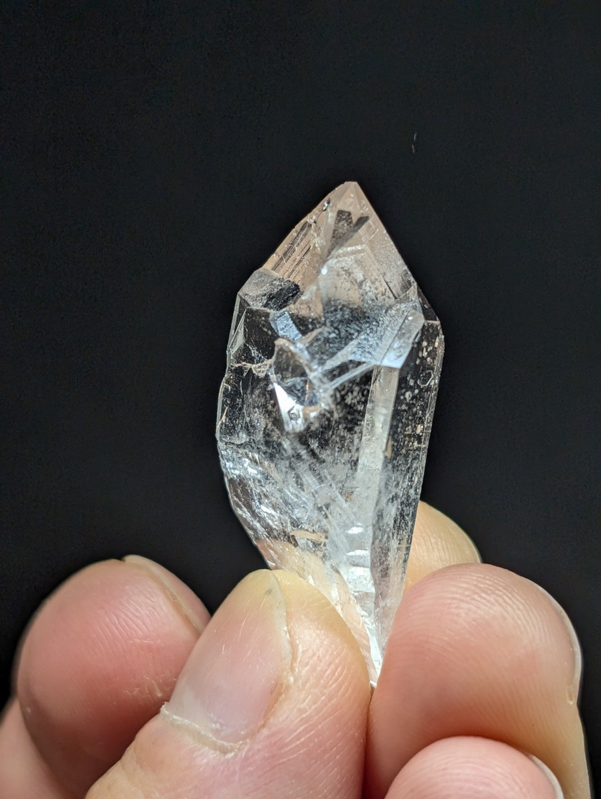 A clear, faceted quartz crystal with natural inclusions and a pointed tip.