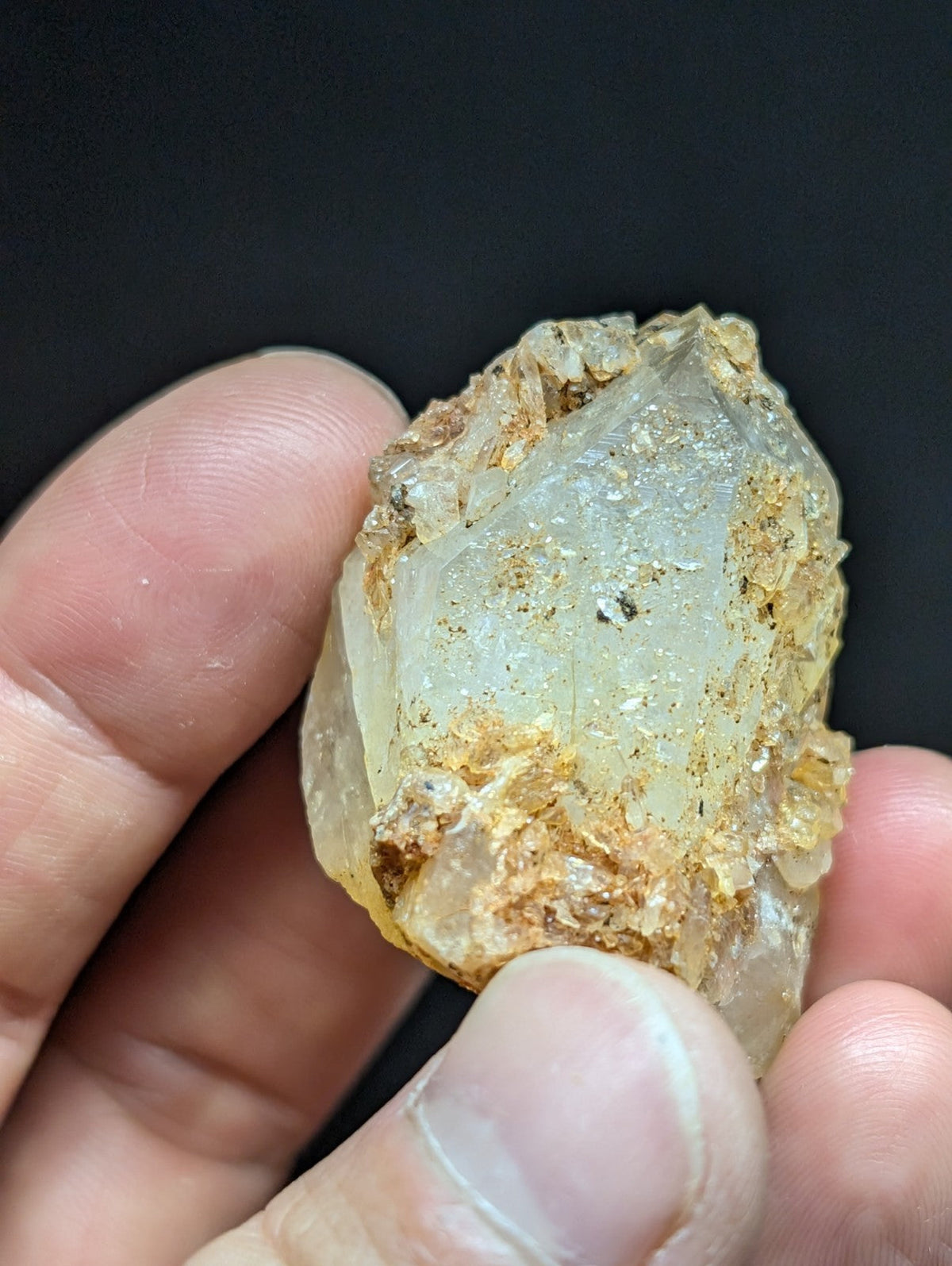 A translucent, pale quartz crystal with golden-brown mineral inclusions and a rough, natural surface.