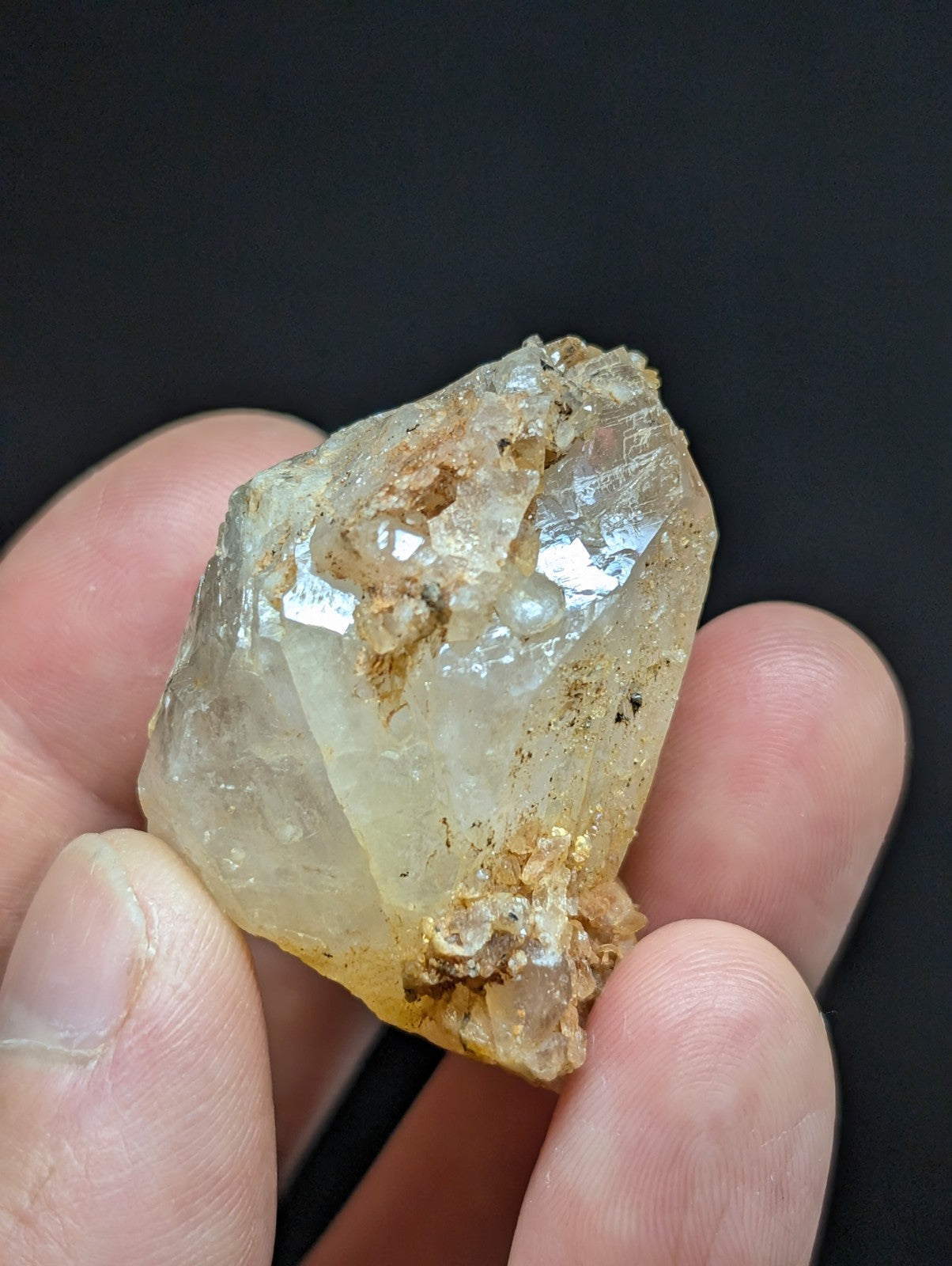 A translucent, pale yellow crystal with visible internal facets and earthy brown matrix material.