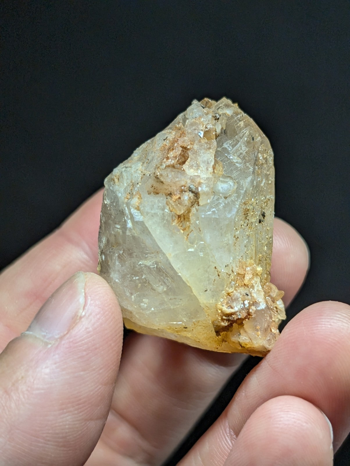A translucent, pale yellow crystal with rough edges and embedded brownish mineral inclusions.