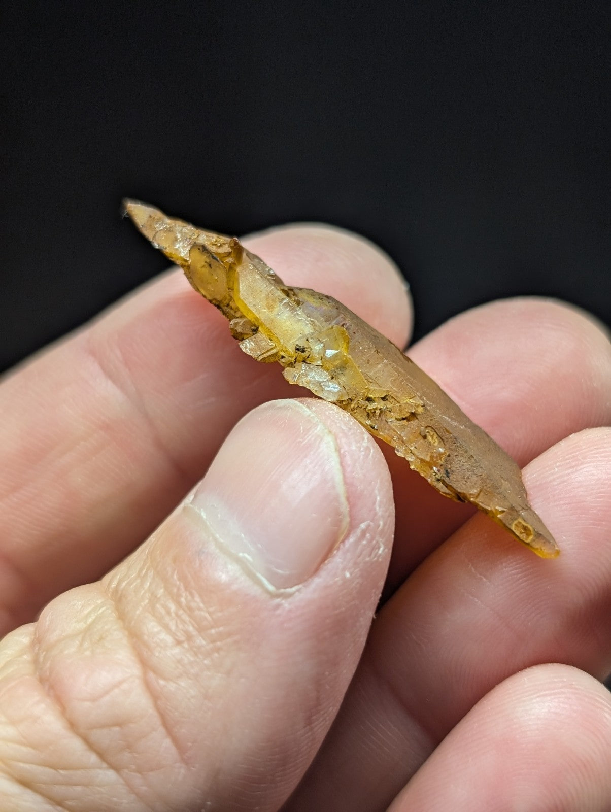 A translucent amber-colored, irregularly shaped piece of fossilized resin with visible inclusions and a slightly rough texture.