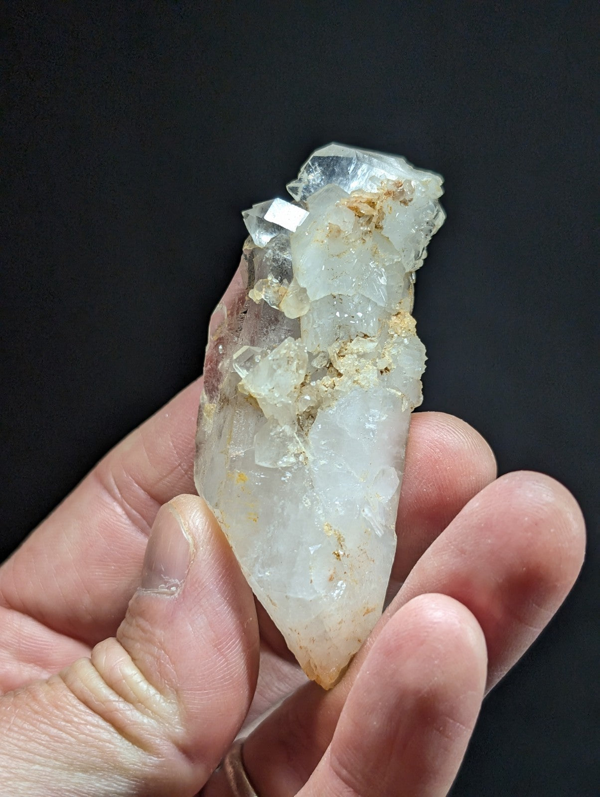 A translucent, crystalline quartz specimen with a pointed tip and embedded golden mineral inclusions.