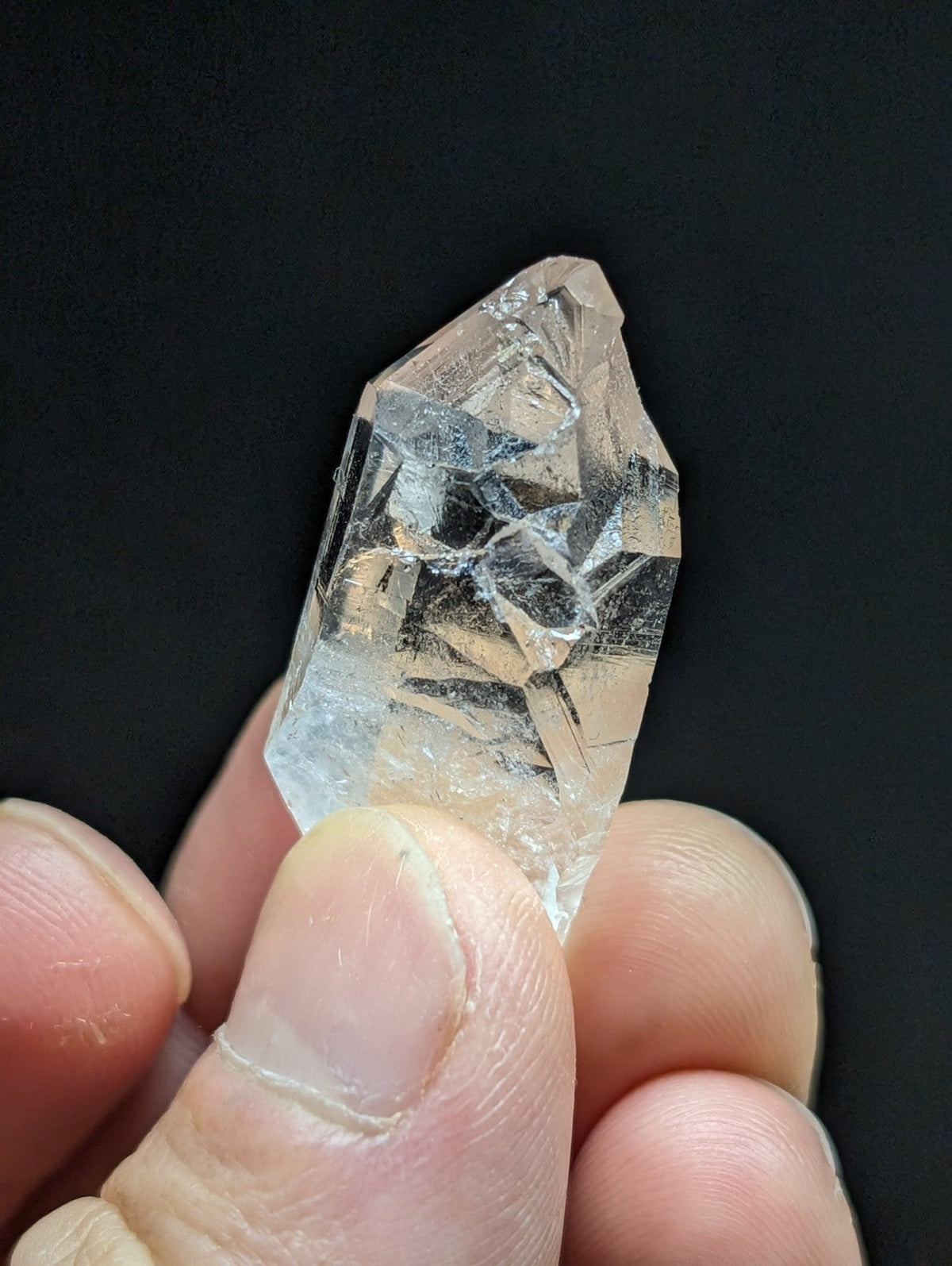 A clear, faceted quartz crystal with a pointed tip and visible internal inclusions.