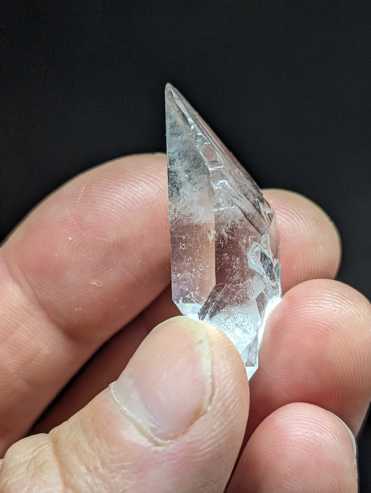 A clear, faceted quartz crystal with natural inclusions and a pointed tip.