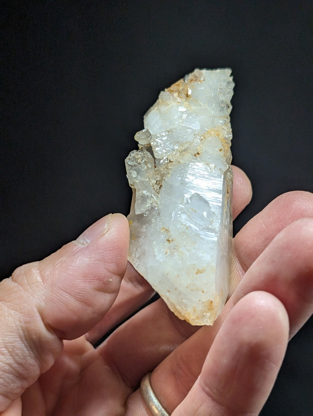 A translucent, pale white quartz crystal with visible internal striations and a rough, jagged surface.