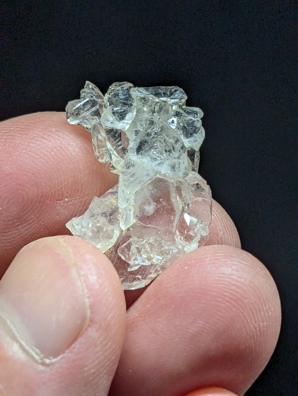 A translucent, clear crystal cluster with jagged edges and a rough, natural formation.