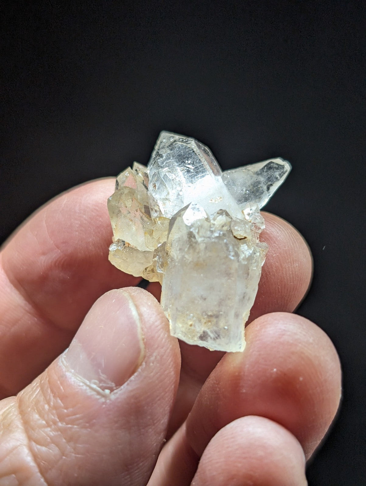 A translucent, pale yellowish quartz crystal cluster with sharp, angular facets and a slightly cloudy base.