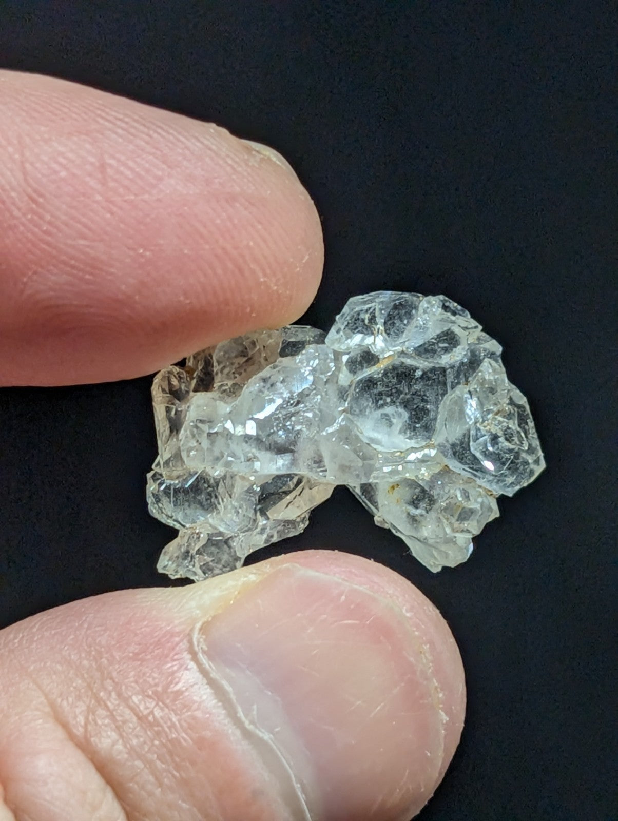 A translucent, irregularly shaped piece of glass with a crystalline texture and clear, faceted surfaces.