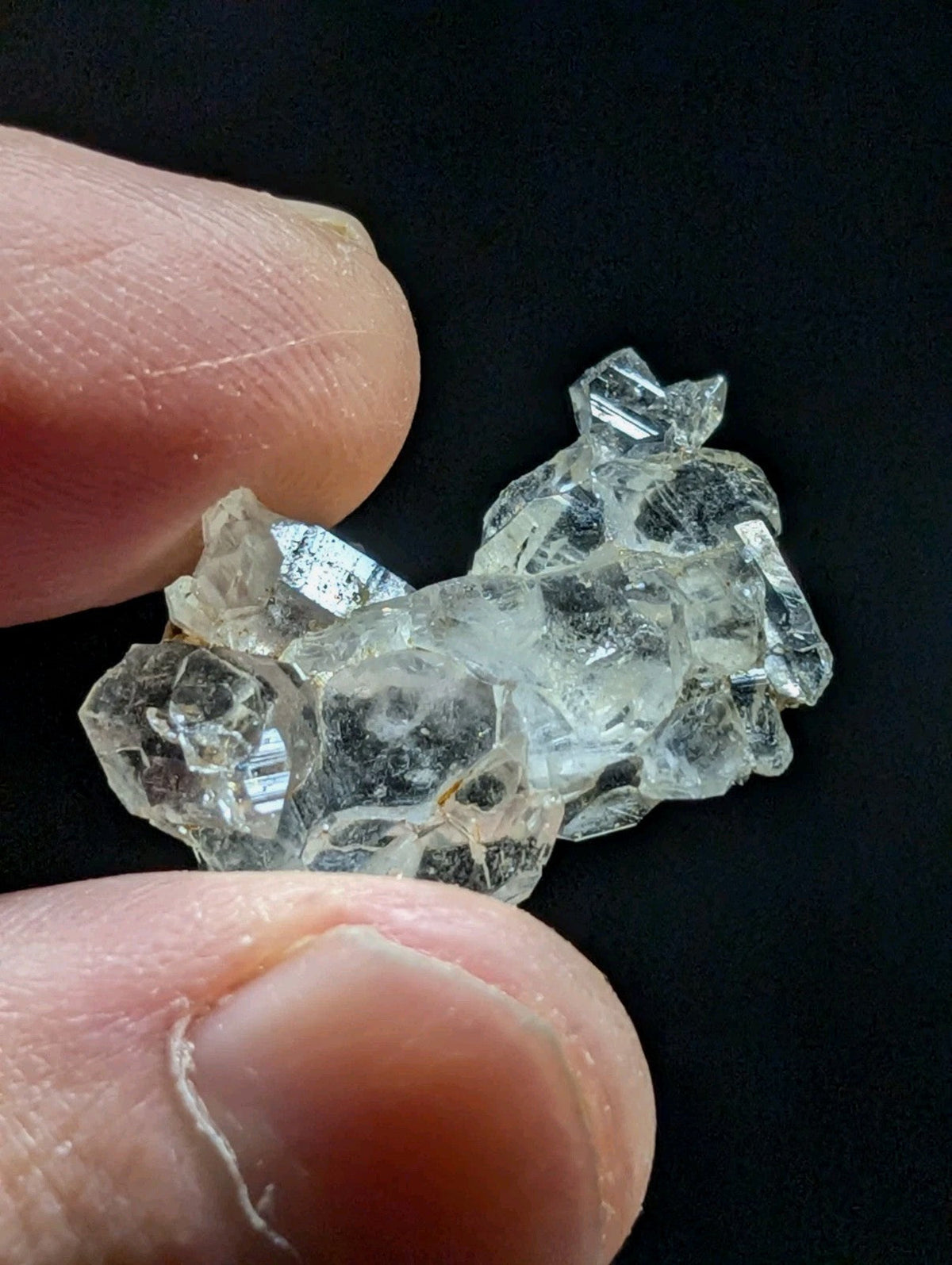 A clear, faceted crystal cluster with sharp edges and a translucent appearance.