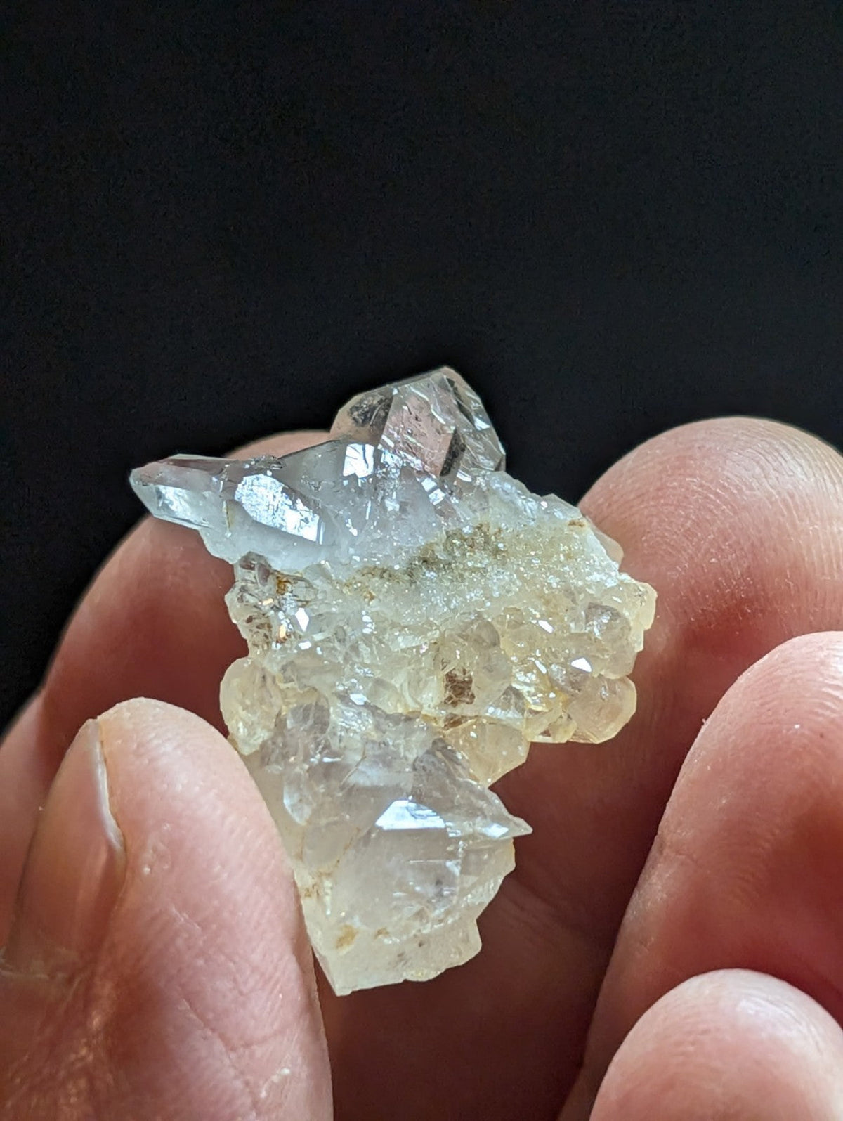 A translucent, pale blue and white quartz crystal cluster with sharp facets held gently in a hand.