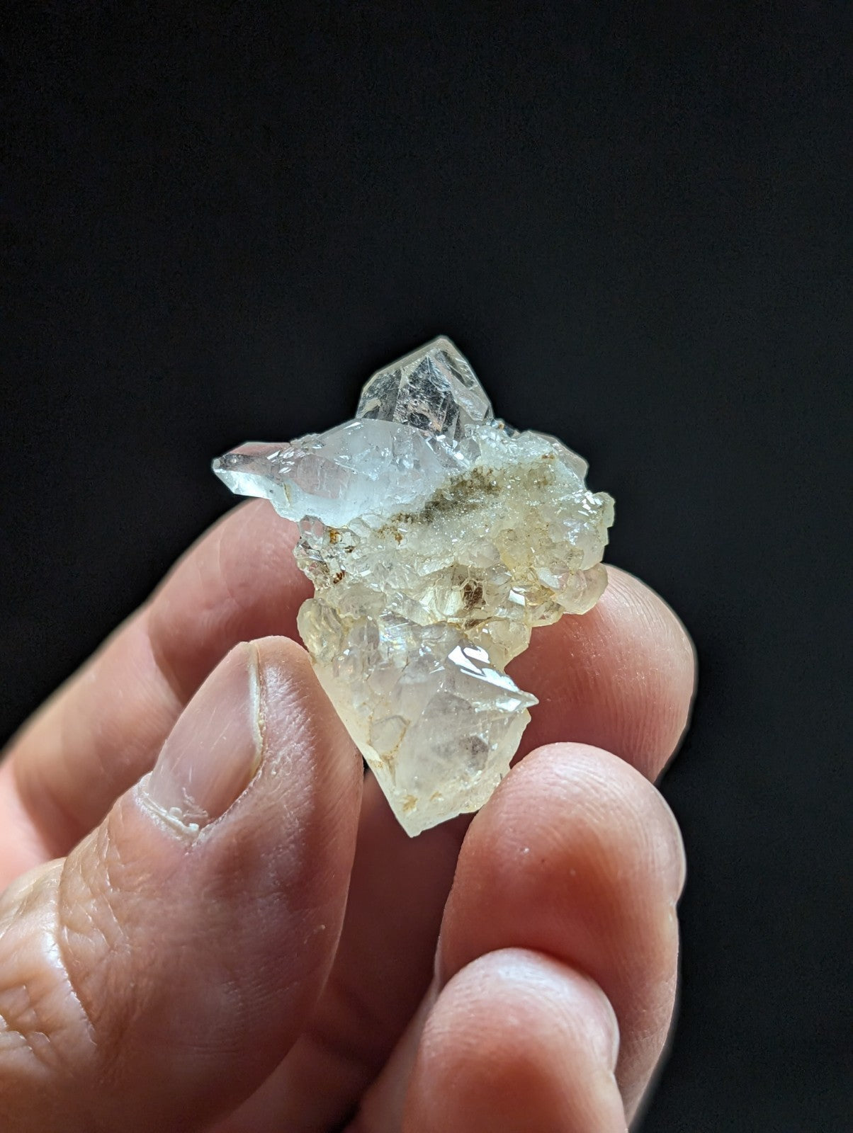 A translucent, pale blue and white quartz crystal cluster with jagged edges held in a hand.