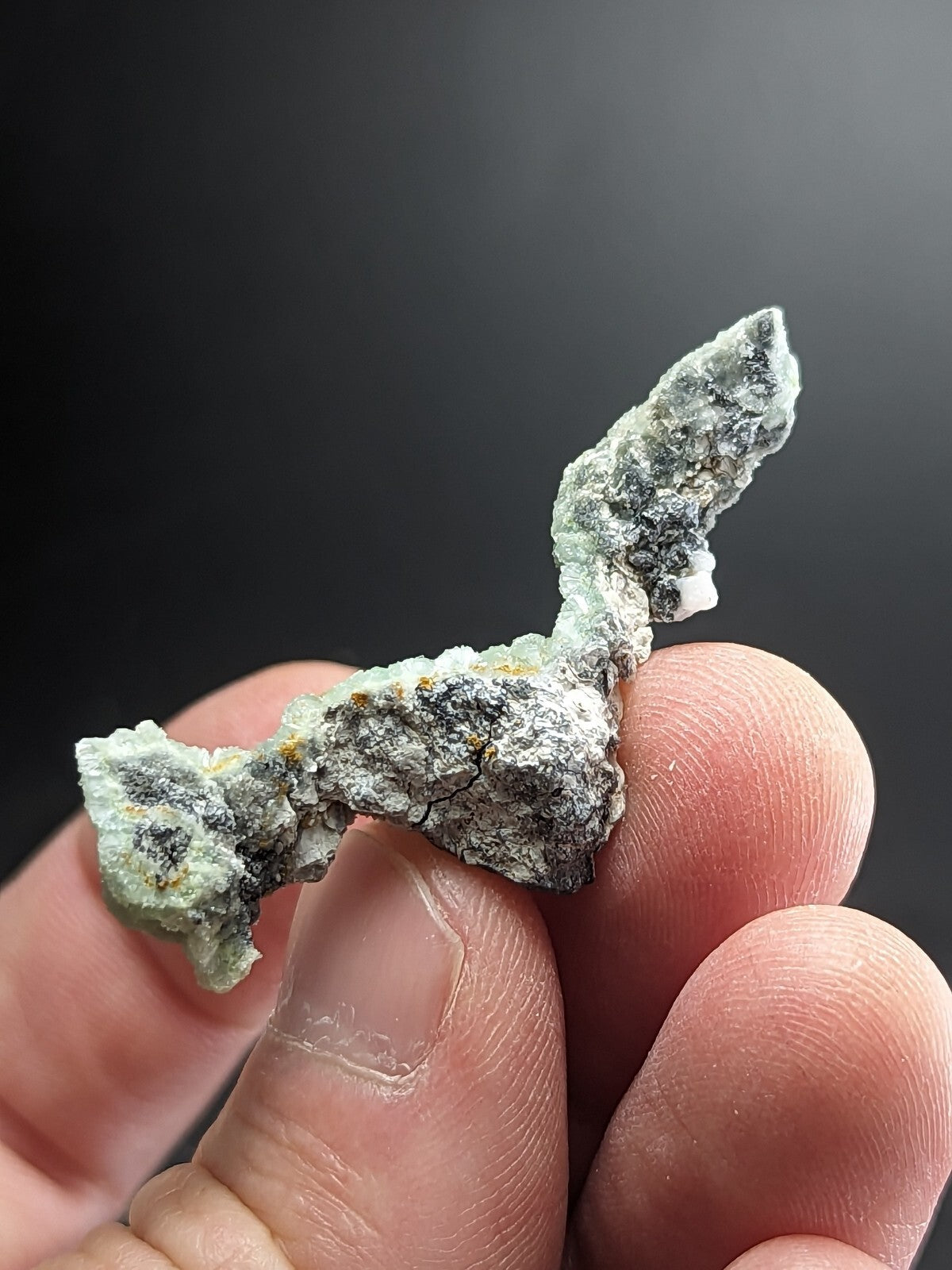 A textured, irregularly shaped mineral specimen with a mottled green and gray surface.