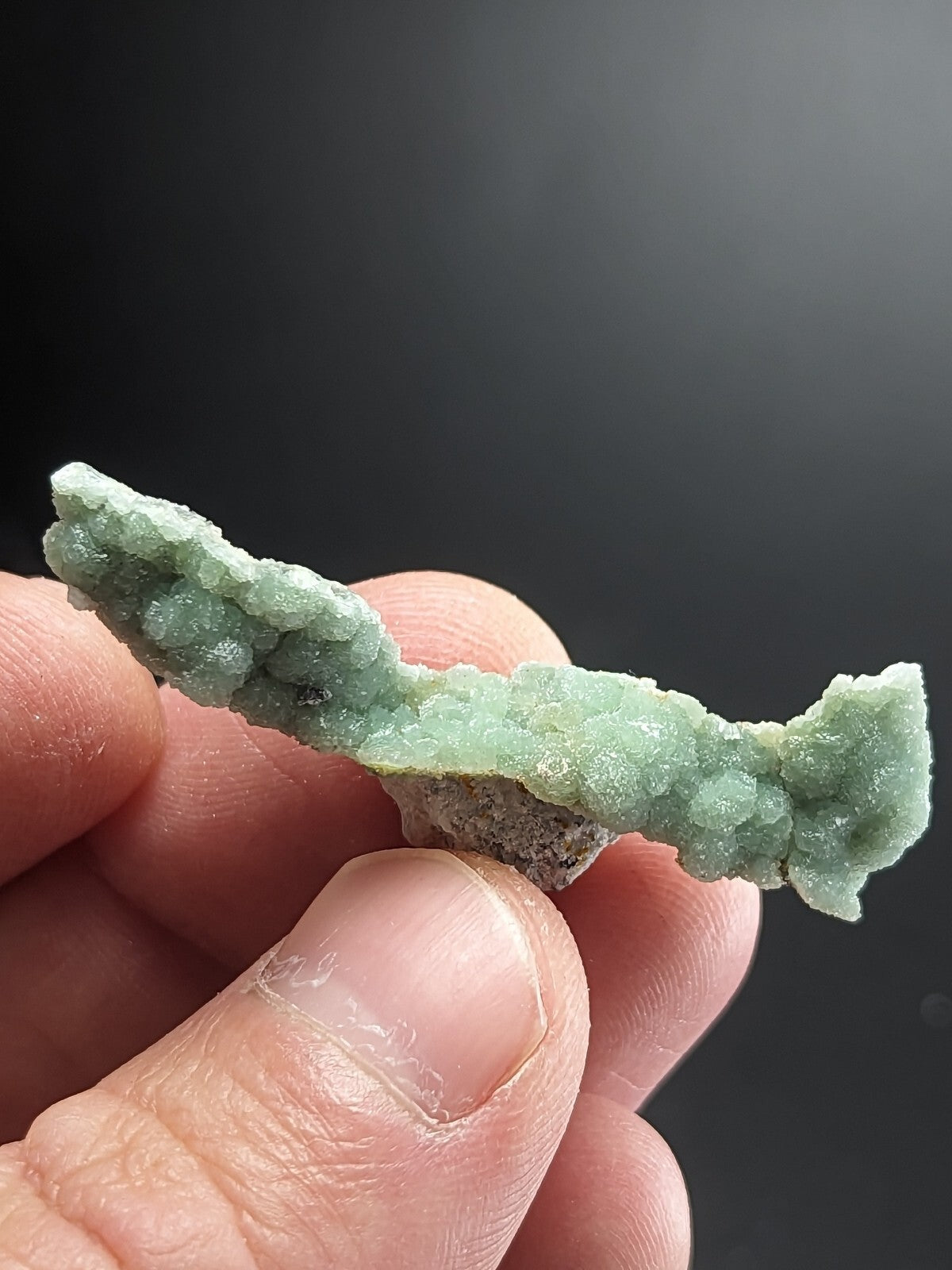 A delicate, light green mineral specimen with a crystalline texture and irregular shape.