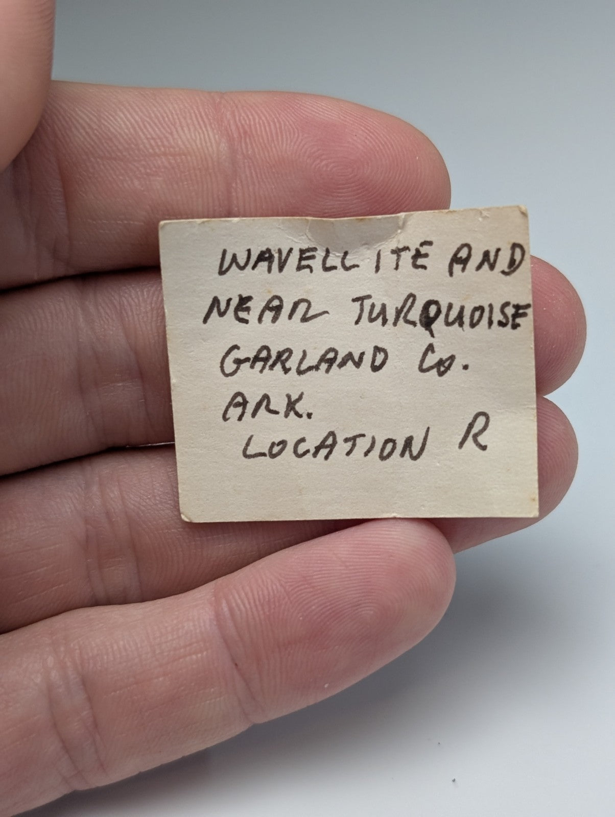 A weathered off-white paper label with handwritten black ink detailing unique wavellite mineral origins from garland county arkansas