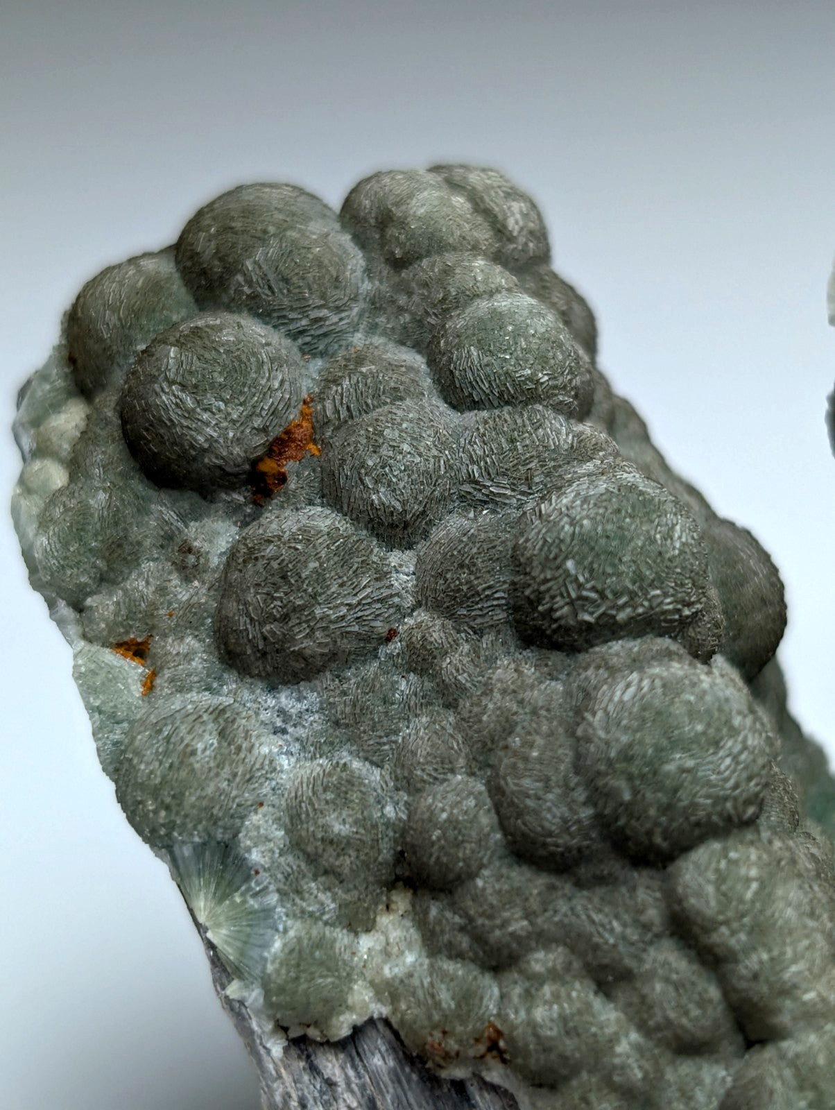 Uv reactive green wavellite cluster with rounded bulbous gray green formations and orange inclusions from mauldin mountain