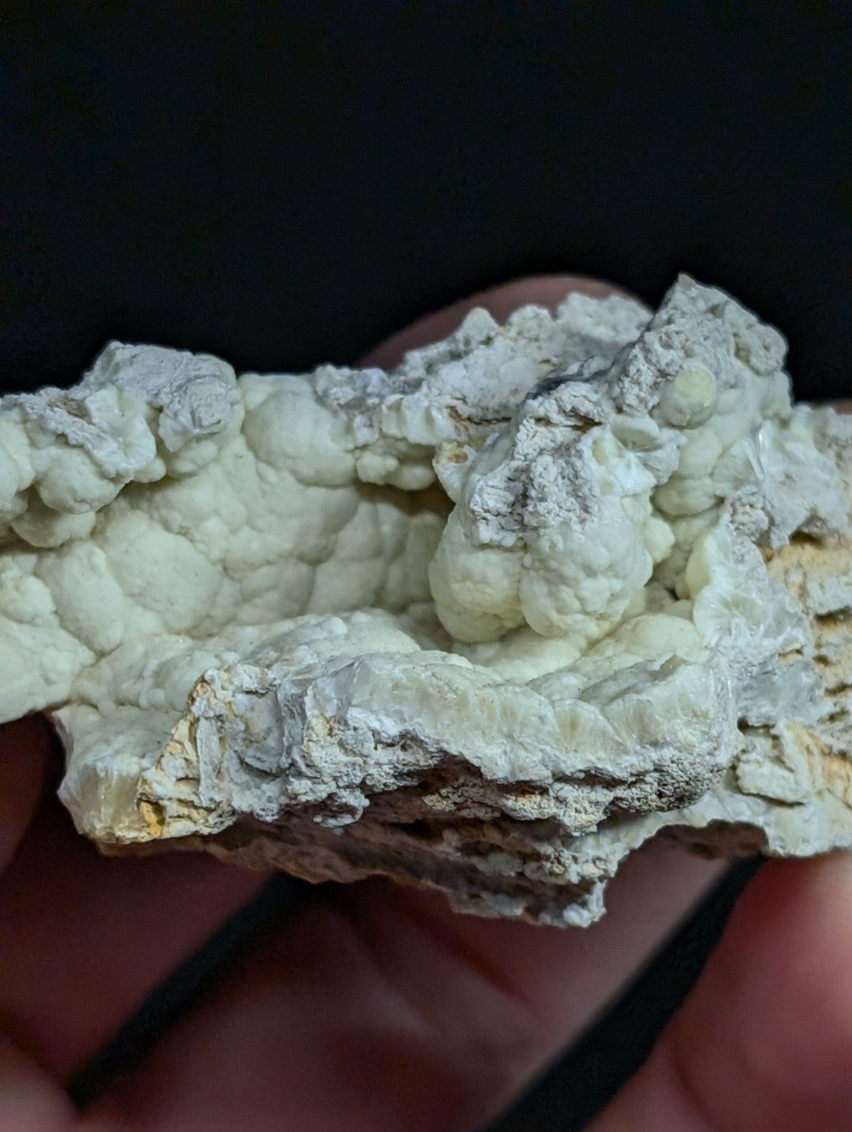 A textured, off-white mineral specimen with a rough, bumpy surface and subtle grayish patches.