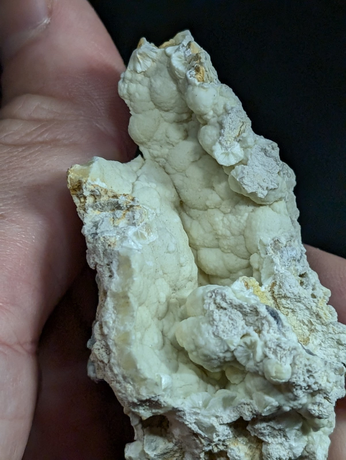 A pale, textured mineral specimen with a bumpy, clustered surface and subtle yellowish streaks.