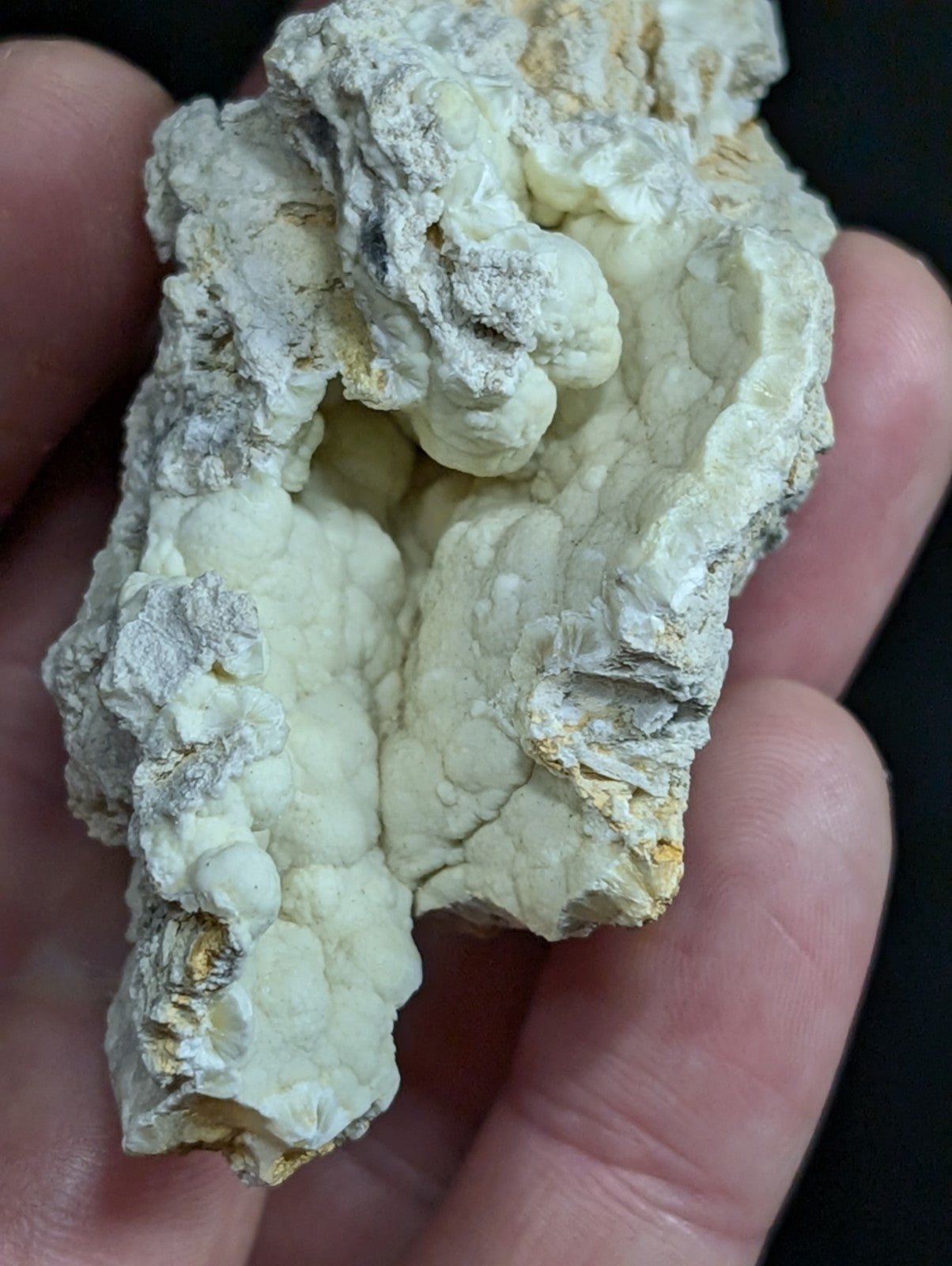 A rough, off-white mineral specimen with a textured, bumpy surface and subtle yellowish patches.