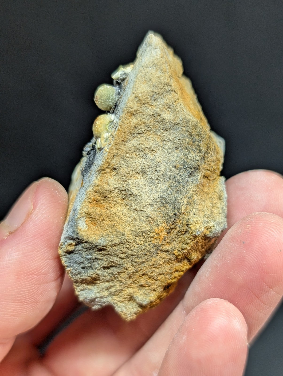 A rough, irregularly shaped mineral specimen with a mottled surface of yellowish-brown and gray tones.